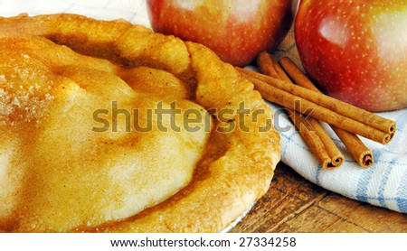 Freshly baked apple pie with apples on a rustic wood surface.