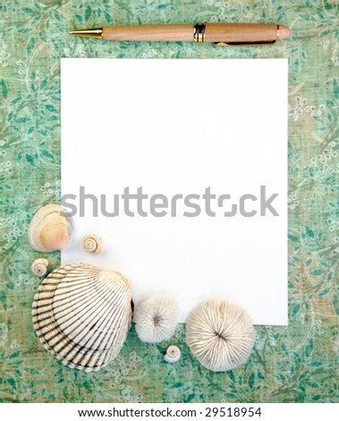 Notepaper and pen with sea shells on a green background.
