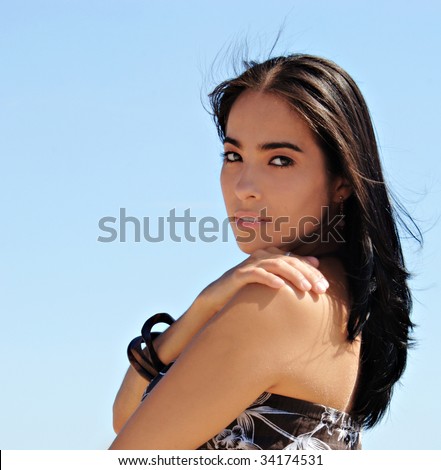 Young Hispanic woman portrait against a blue sky.