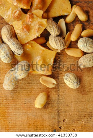Peanut brittle and nuts laying on a wooden table.