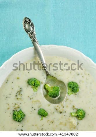 Bowl of cream of broccoli soup on a blue tablecloth.