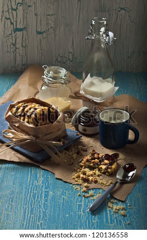 Side view of peanut biscuits, jars with jam and condensed milk, bottle with milk on blue crackled background