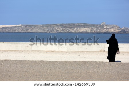 Silhouette of arab woman watching the sea in Essaouria, Morocco