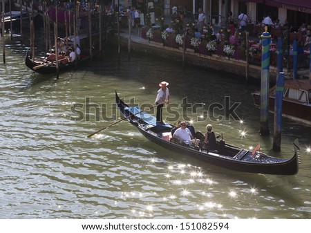 VENICE-AUGUST 18: Gondoliers ride gondola on the Grand Canal in Venice on August 18, 2013. Gondola is one of the symbols of Venice and major mode of touristic transport in Venice, Italy.