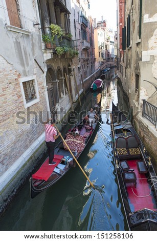 VENICE-AUGUST 18: Gondoliers ride gondolas on the canals of Venice on August 18, 2013. Gondola is one of the symbols of Venice and major mode of touristic transport in Venice, Italy.