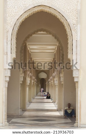 CASABLANCA, MOROCCO - JULY 23: Local people sitting at an arch of King Hassan II Mosque on July 23, 2014 in Casablanca, Morocco. It is the largest Mosque in the country