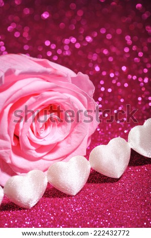 chain of white textilehearts with pink rose on pink sparkle background