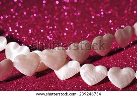 chain of white textilehearts on pink sparkle background