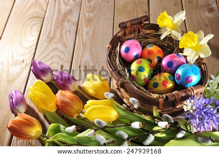 Easter nest with colored henÃ¢Â?Â?s eggs, narcissus, hyacinth and pussy willow on wooden board