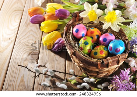 Easter nest with colored henâ??s eggs, narcissus, hyacinth and pussy willow on wooden board