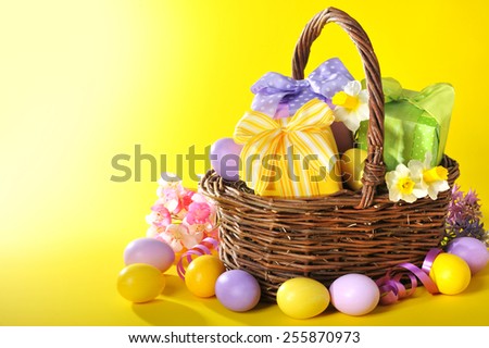colorful easter presents with bow in easter basket with narcissus and painted easter eggs