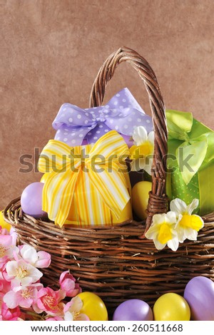 colorful easter presents with bow in easter basket with narcissus and painted easter eggs