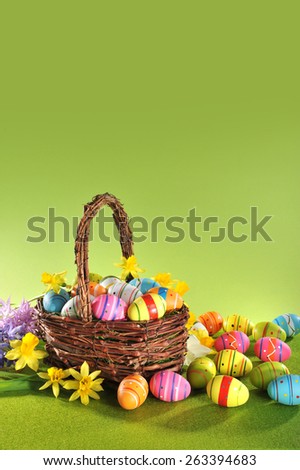 colorful easter eggs and narcissus in easter basket on grass