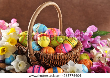 Easter basket with many painted easter eggs, narcissus and catkin