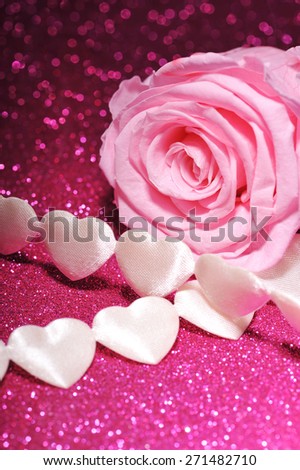 chain of white textilehearts with pink rose on pink sparkle background