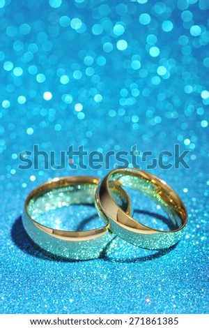 Two golden rings on turquoise glitter background