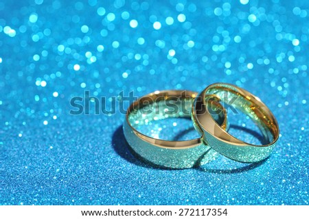 Two golden rings on turquoise glitter background