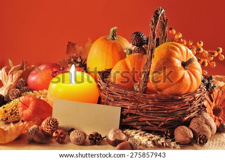 Thanksgiving - different pumpkins, nuts, maize cob and apple in rattan basket with candlelight and copyspace