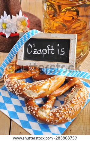 The beer is tapped - original bavarian salted soft pretzels with Oktoberfest beer mug and costume hat from Germany