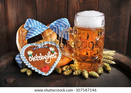 original bavarian Oktoberfest big soft pretzel with beer mug, hops and gingerbread heart from Germany on old beer barrel