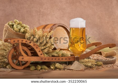 beer glass with wood barrel with wheelbarrow, hops, wheat, grain, barley and malt