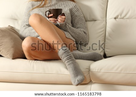 Perfect woman waxed legs in winter sitting on a couch in the living room at home