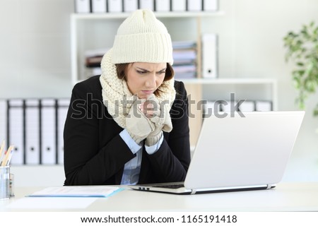 Cold angry executive working at office with a heater failure in winter