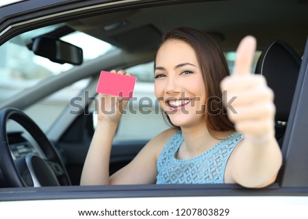 Happy driver showing a blank card or license with thumbs up inside a car