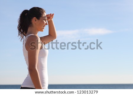 Beautiful girl watching the sea with a hand on her forehead