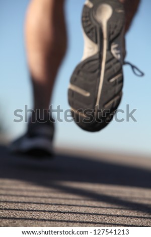Unfocused Man Shoes Running On The Asphalt With The Sky In The Background