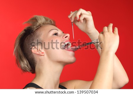 Woman piercing the tongue herself on a red background