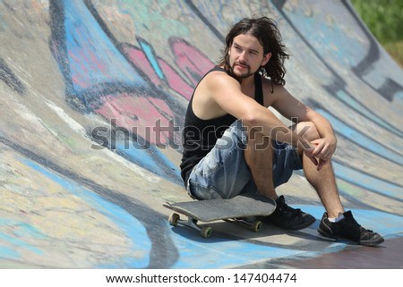 Portrait of a boy sitting with a skateboard on a half pipe with graffiti
