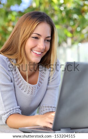 Beautiful woman happy browsing internet in her laptop outdoor