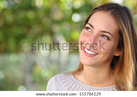 Beautiful Woman Smiling With A Perfect Teeth And Looking Above With A Green Unfocused Background