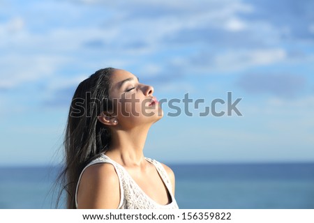 Beautiful arab woman breathing fresh air in the beach with a cloudy blue sky in the background