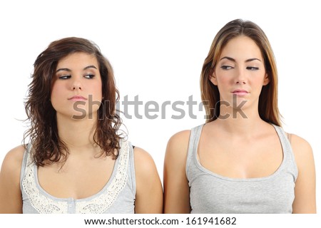 Two girls looking each other angry isolated on a white background Two girls looking each other angry isolated on a white background