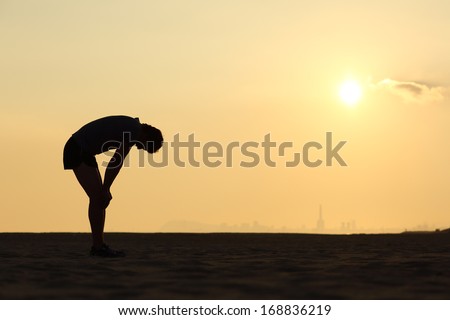 Silhouette Of An Exhausted Sportsman At Sunset With The Horizon In The Background