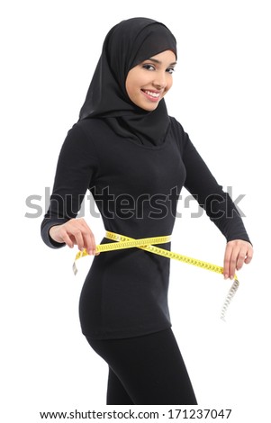 Beautiful arab saudi fitness woman measuring her waist with a tape measure and looking at camera isolated on a white background Beautiful arab saudi fitness woman measuring her waist with a tape measure and looking at camera isolated on a white background