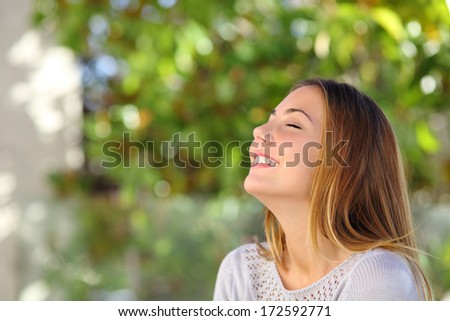 Young happy smiling woman doing deep breath exercises outdoor with a green background