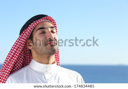 Arab saudi man breathing deep fresh air in the beach with the ocean and horizon in the background