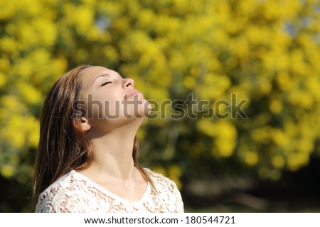 Woman breathing deep in spring or summer with a yellow background
