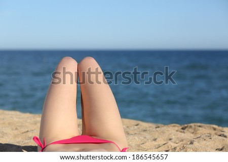 Woman legs sunbathing on the beach with the horizon in the background