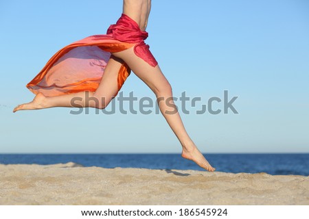 Woman legs jumping on the beach happy with the horizon and sea in the background Woman legs jumping on the beach happy with the horizon and sea in the background