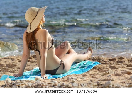 Woman sunbathing on the beach in summer with the sea in the background