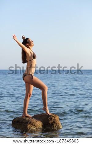 Full body of a beautiful woman breathing on the beach in the middle of the sea