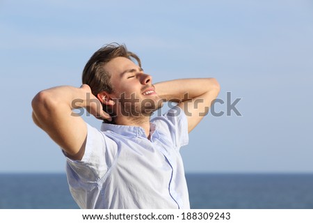 Happy young man breathing deep with hands in the head with the horizon in the background