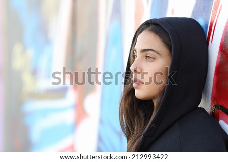 Profile portrait of a skater style teenager girl with an unfocused graffiti wall in the background
