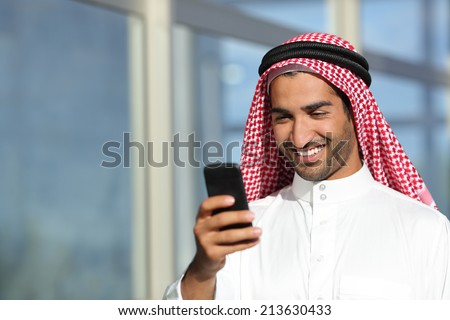 Arab saudi businessman working with his phone with an office building in the background