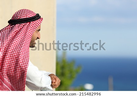 Happy relaxed arab saudi man looking the sea from a balcony of an hotel