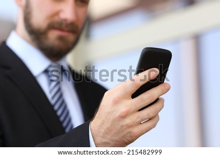 Executive hand using a smartphone in the street with an office building in the background